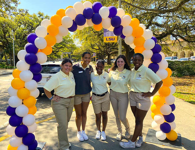 LSU Ambassadors stand under balloon arch.