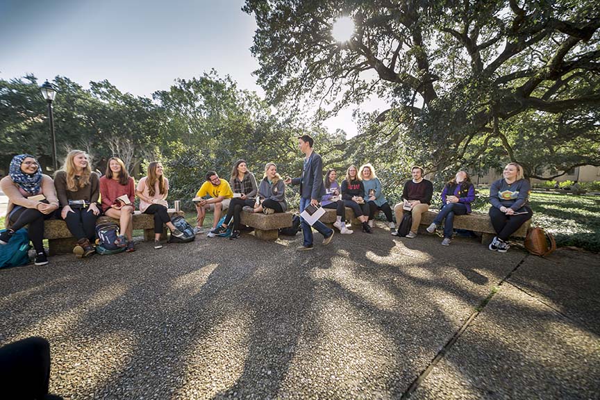 professor delivering a lecture outside in the quad surrounded by students