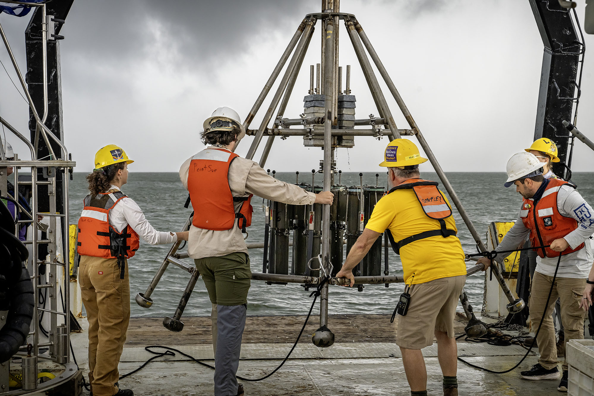 researchers manage a piece of equipment on a platform near the Louisiana coast