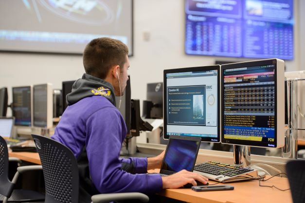 Student works on computer with two monitors