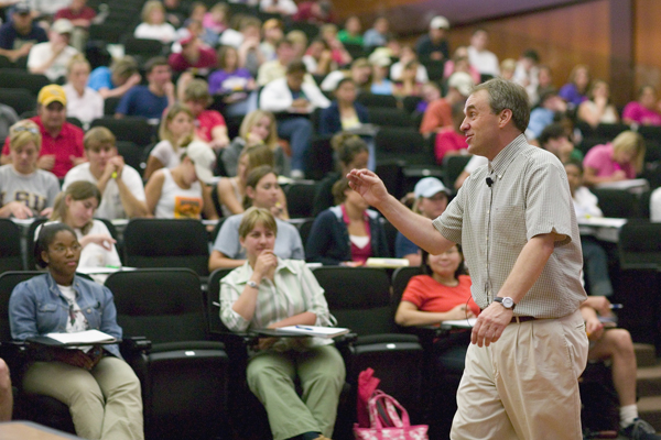 Professor teaching in front of large class. 