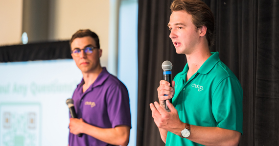 Two male students presnt on stage with microphones