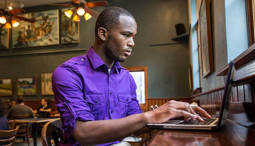 student at laptop in coffee shop